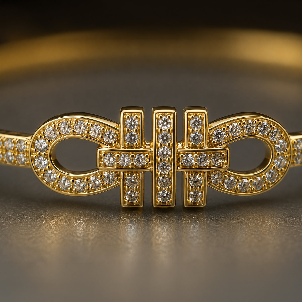 A gold-toned bangle bracelet featuring a central bowtie-like motif paved with small clear stones, shown in a close-up studio shot on a dark reflective surface.