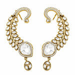 A pair of gold crescent-shaped drop earrings adorned with clear marquise and oval gemstones, set against a plain white background.
