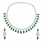 A silver-tone jewelry set featuring a necklace and matching drop earrings, both adorned with small clear stones and a row of oval-cut green emeralds, displayed on a solid white background.