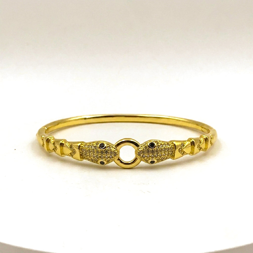 A gold-plated bangle bracelet with a central open ring and two decorative fish-shaped end pieces, photographed on a plain white background.