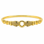 A gold-plated bangle bracelet featuring two detailed fish charms on either side of a central ring, embellished with pavé-set clear stones and small black inlays.