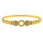 A gold-plated bangle bracelet featuring two fish-shaped charms paved with small clear stones and accented with tiny black gemstones, set against a plain white background.