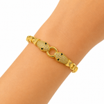 A gold snake bracelet with pavé-set clear stones and small black eye details, shown worn on a person's wrist against a plain white background.