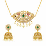 Gold-plated Indian jewelry set featuring a necklace and matching earrings. The necklace has an ornate filigree pendant with a green emerald center, pink gemstone floral accents, and dangling white pearls.
