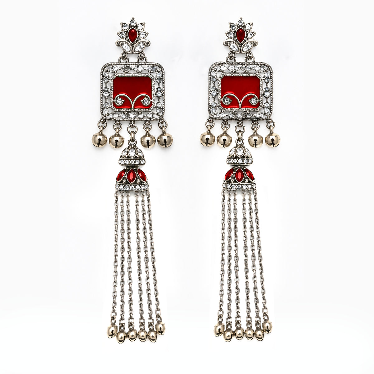 A pair of traditional Indian silver-toned dangle earrings with red enamel panels, clear pavé stones, and dangling silver bells, shown against a plain white background.