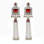 A pair of traditional Indian silver-toned dangle earrings with red enamel panels, clear pavé stones, and dangling silver bells, shown against a plain white background.