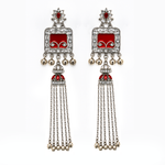 A pair of traditional Indian silver-toned dangle earrings with red enamel panels, clear pavé stones, and dangling silver bells, shown on a plain white background.