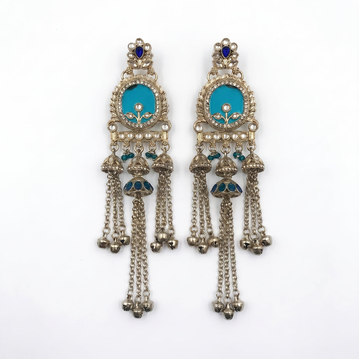 A pair of ornate silver-toned Indian jhumka earrings with turquoise blue enamel inlays, small pearl-like beads, and dangling bell chains, shown on a plain white background.