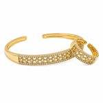 A gold-toned open cuff bangle bracelet featuring pavé-set clear stones along the front band, shown on a plain white background.