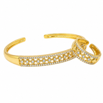 A gold-toned open cuff bracelet featuring pavé-set clear stones in a repeating floral pattern, shown on a plain white background.