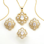 Gold jewelry set featuring a pendant necklace, ring, and two matching earrings, all with floral clover-shaped designs set with clear crystals on a white background.