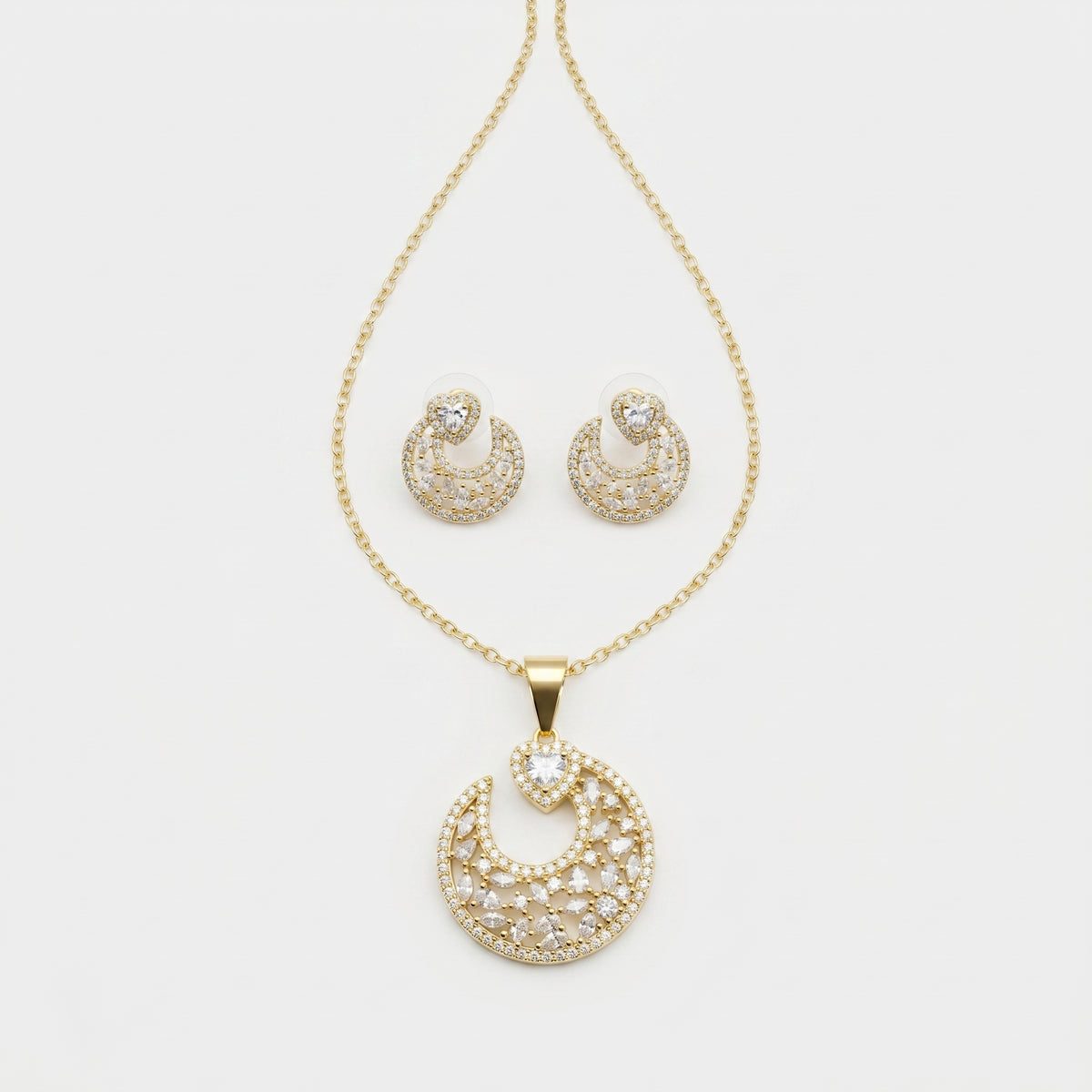 Gold crescent moon jewelry set featuring a pendant necklace and matching stud earrings, embellished with clear pavé stones on a white background.